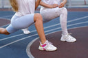 Dos atletas picsil fortaleciendo sus piernas con walking lunges o zancadas